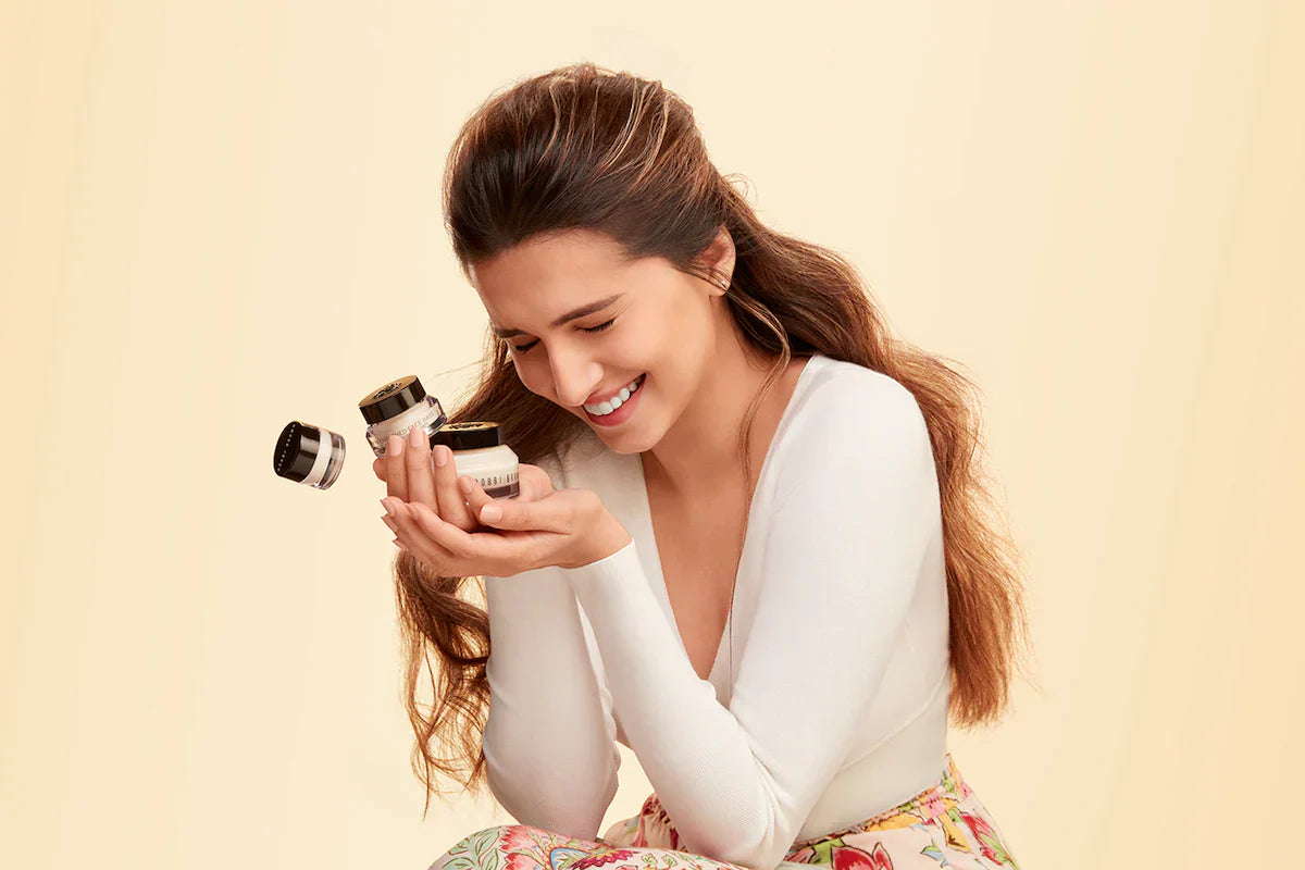 Smiling woman holding Bobbi Brown skincare cream jars, luxury beauty product focus