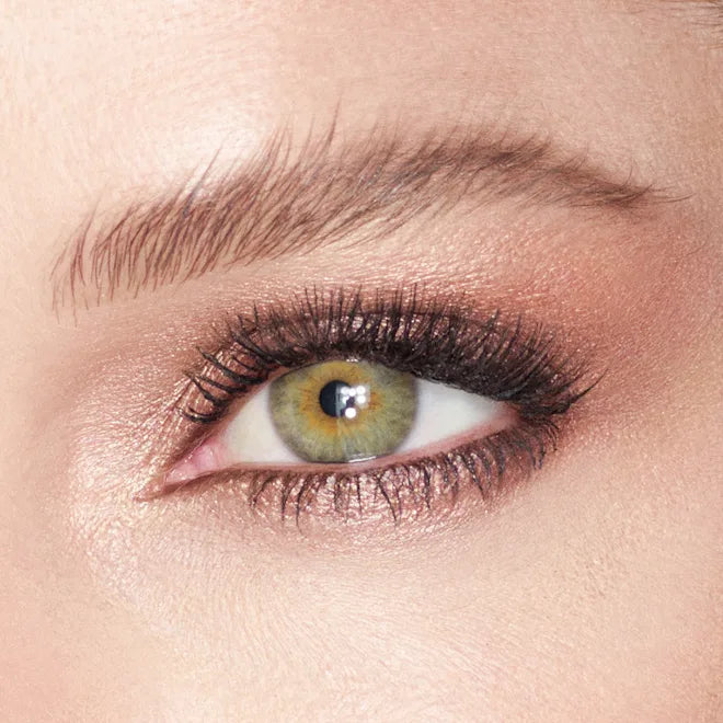 Close-up of green eye with shimmery rose gold eyeshadow and voluminous black lashes