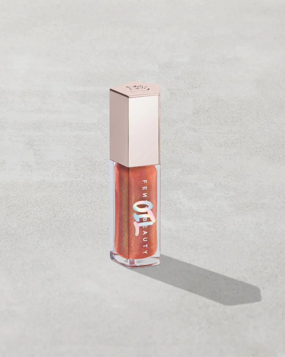 Shimmery rose gold lip gloss in clear tube with metallic cap on light background