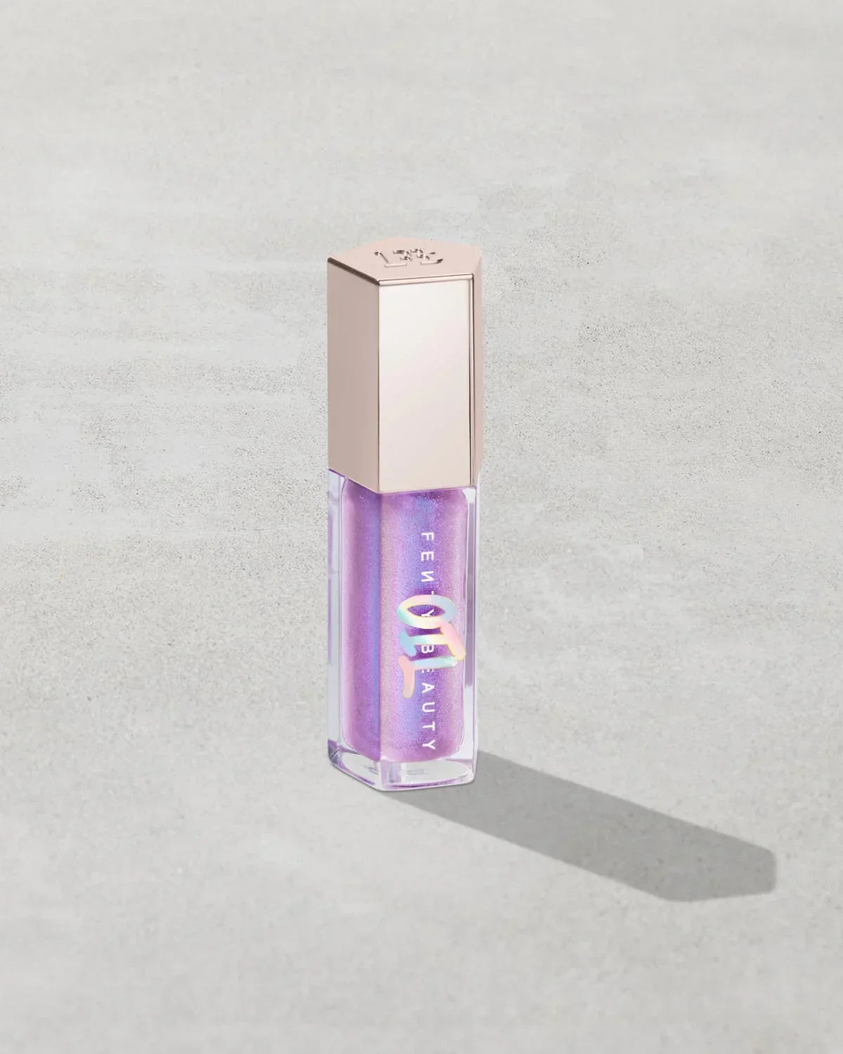 Iridescent purple lip gloss with metallic cap on light gray background