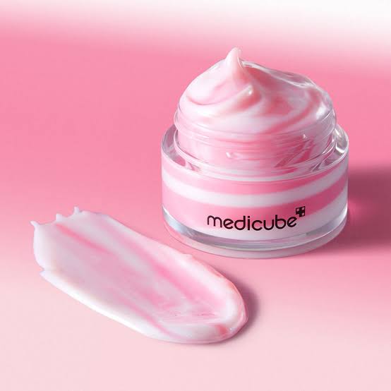 Pink and white swirl face cream in a clear jar with medicube label on a pink background