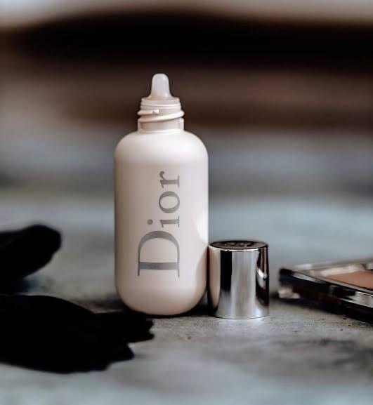 Dior liquid foundation bottle with metallic cap on a makeup table