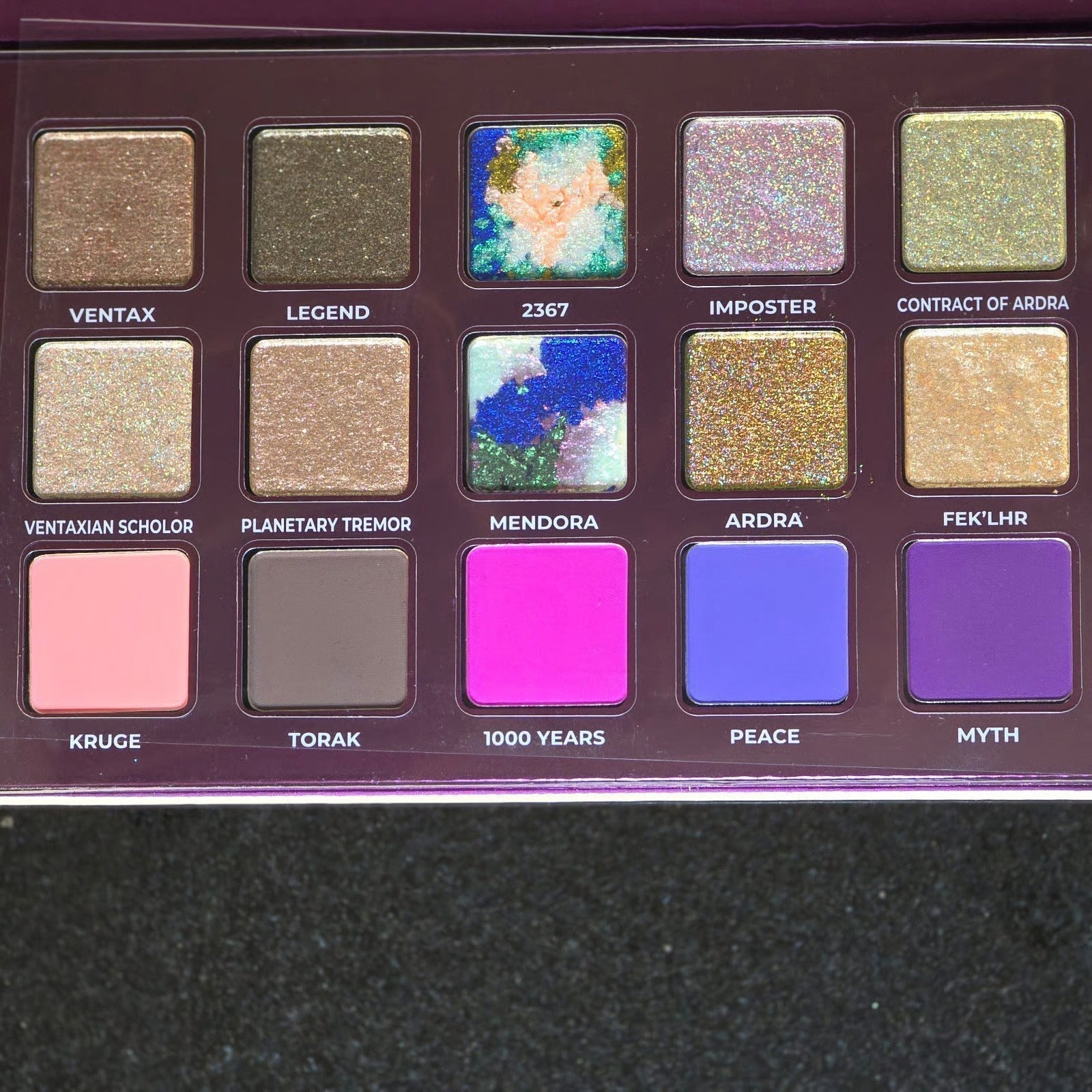 Colorful eyeshadow palette with 15 shimmery and matte shades in pink, blue, gold, and purple.